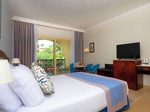 A hotel room with a bed, a desk, a television, and a balcony with chairs. - Stella Gardens Resort Spa Makadi Bay (Makadi Bay)