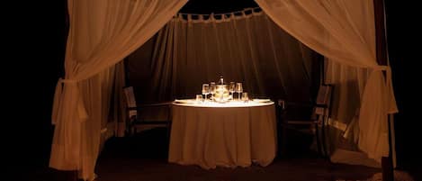 An outdoor dining setup with a table and chairs under a canopy.