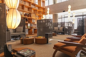 Ein großzügiger Lounge-Bereich mit verschiedenen Sitzmöglichkeiten, darunter Sofas und Sessel, einem Couchtisch und einer Bücherwand mit Dekoration.