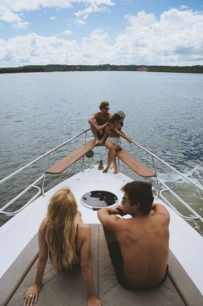 Ein Boot mit einem Deck, einer Sitzgruppe und Blick auf das Wasser sowie das entfernte Land.