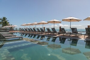 Ein Poolbereich mit Liegestühlen und Sonnenschirmen mit Blick auf den Ozean.