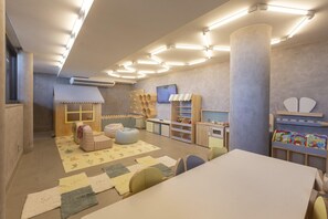 A children's playroom with a large table, chairs, storage units, and a play area. - Ritz Barra De São Miguel (Maceió)