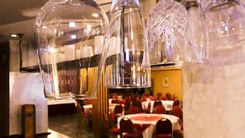 Ein Restaurantinnenraum mit hängenden Glaskandelabern und gedeckten Tischen.