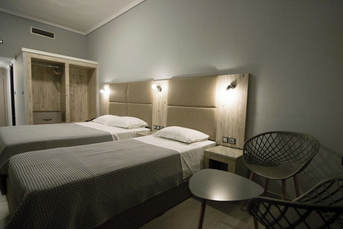 Habitación de hotel con dos camas, una silla y un armario.