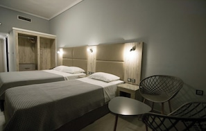 Habitación de hotel con dos camas, una silla y un armario.