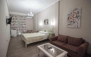 A bedroom with a bed, a nightstand, a sofa, a coffee table, a painting, and a chandelier. - Vienni (Orestiada)