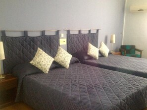 A hotel room with two beds, each with a quilted headboard and matching pillows. - Vienni (Orestiada)