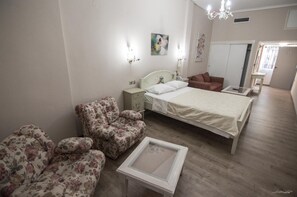 A bedroom with a bed, two chairs, a bedside table, a dresser, and a mirror. - Vienni (Orestiada)