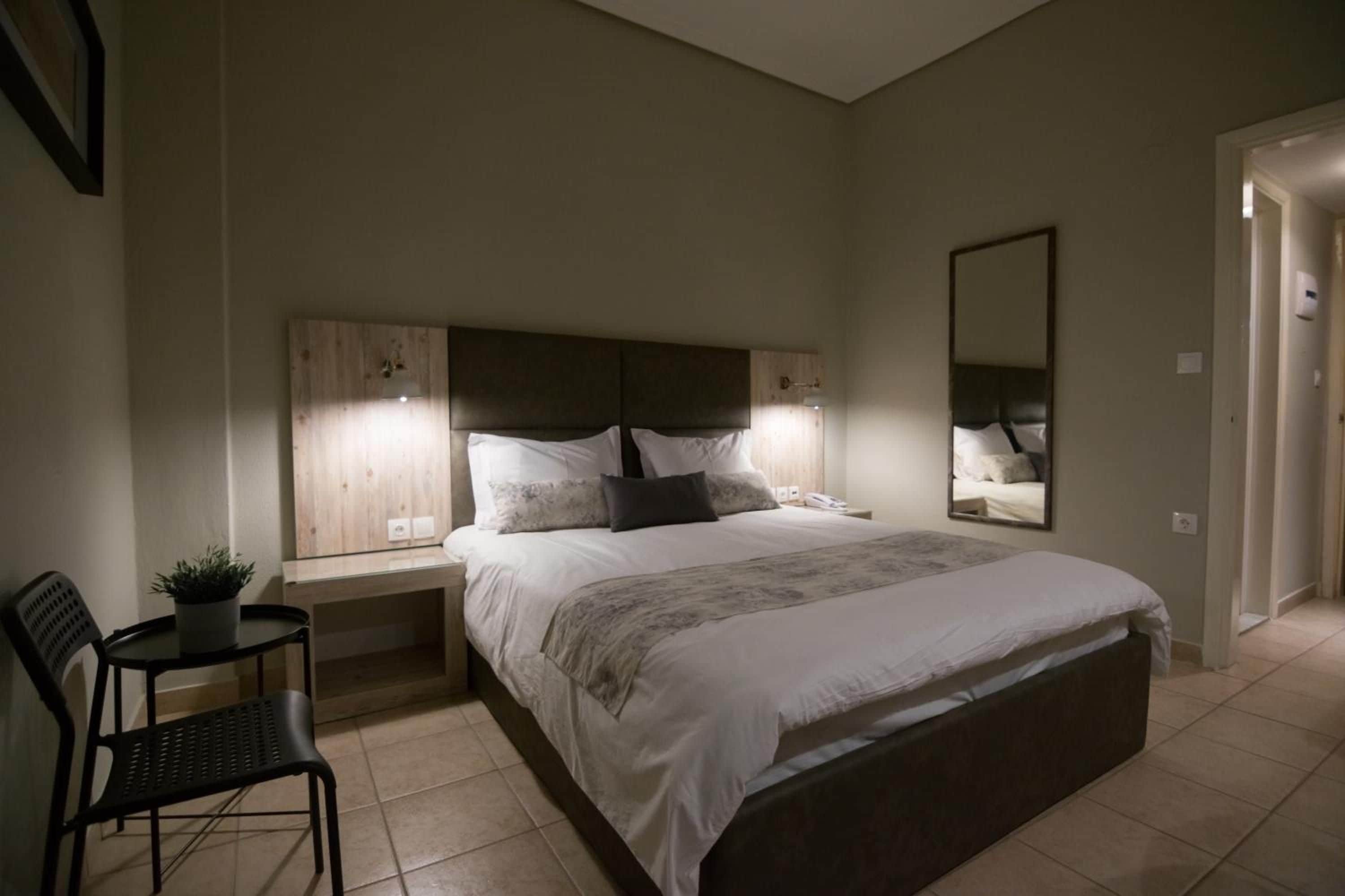 Ein Schlafzimmer mit einem Bett, Nachttischen, einem Sessel, einem Spiegel und einer Topfpflanze.