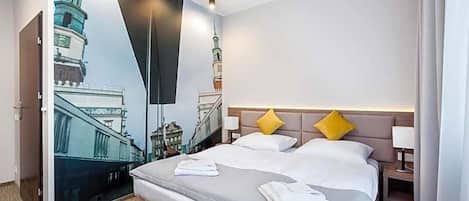 A hotel room with a large bed, two pillows, a nightstand, and a wall mural of a building.