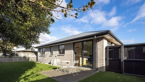 A modern house with a patio, a fenced backyard, and a garage. - Spacious Hornby Stay | 3BR | Sleeps 8 | Garage (Christchurch)