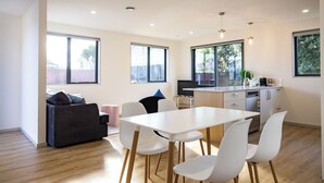 A modern kitchen with a dining area, white furniture, and large windows. - Spacious Hornby Stay | 3BR | Sleeps 8 | Garage (Christchurch)