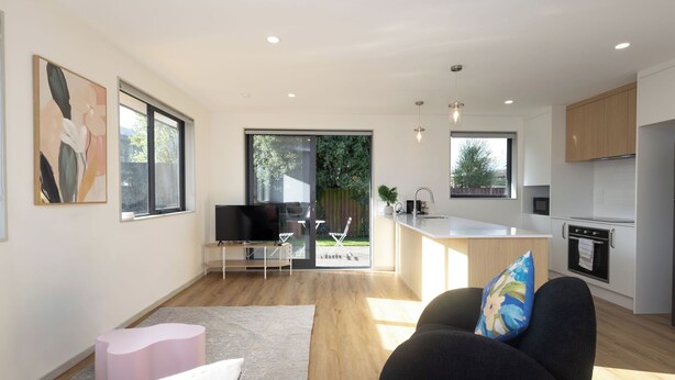 A modern kitchen with a central island, a dining area with a table and chairs, and a living room with a sofa and a TV. - Spacious Hornby Stay | 3BR | Sleeps 8 | Garage (Christchurch)