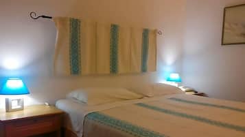 Una camera d'albergo con un letto, due lampade da comodino, un tavolino e una tenda.