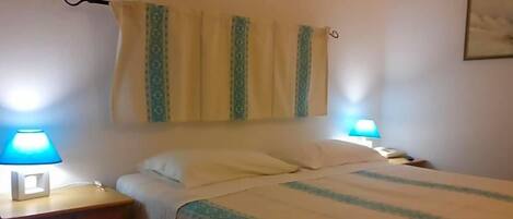 A hotel room with a bed, two bedside lamps, a nightstand, and a curtain.