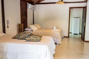 Habitación de hotel con dos camas, teléfono junto a la cama, unidad de aire acondicionado y un pasillo que lleva a una puerta.
