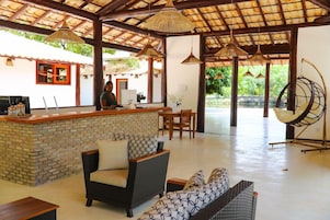 Una zona de recepción con un mostrador de ladrillo, muebles de mimbre y lámparas colgantes.