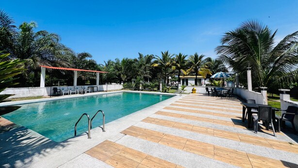 A swimming pool with a wooden deck, lounge chairs, and a covered seating area.