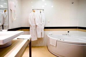 A bathroom with a bathtub, a towel rack with robes, and a mirror.