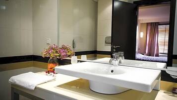 Un baño moderno con un lavabo blanco grande, un espejo y un florero con flores.