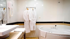 Un baño con bañera, un perchero con batas y un espejo.