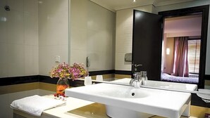 Un baño moderno con un lavabo blanco grande, un espejo y un florero con flores.