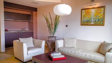 Una sala de estar moderna con un sofá, dos sillones, una mesa de centro, un juego de ajedrez, un jarrón con plantas y un cuadro en la pared.