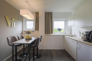 A modern kitchen with a dining area, a coffee machine, and a window with curtains. - Viu2h (Hannover)