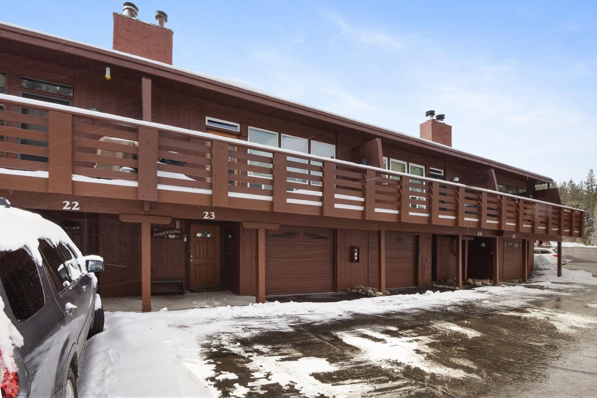 Un immeuble à plusieurs étages, avec des portes de garage numérotées, une allée couverte et un sol recouvert de neige.