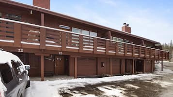 A multi-story building with numbered garage doors, a covered walkway, and a snow-covered ground.