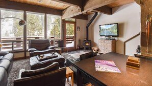 A cozy living room with a fireplace, leather sofas, a dining table, and a TV. - Alpine Manor Retreat (Olympic Valley)