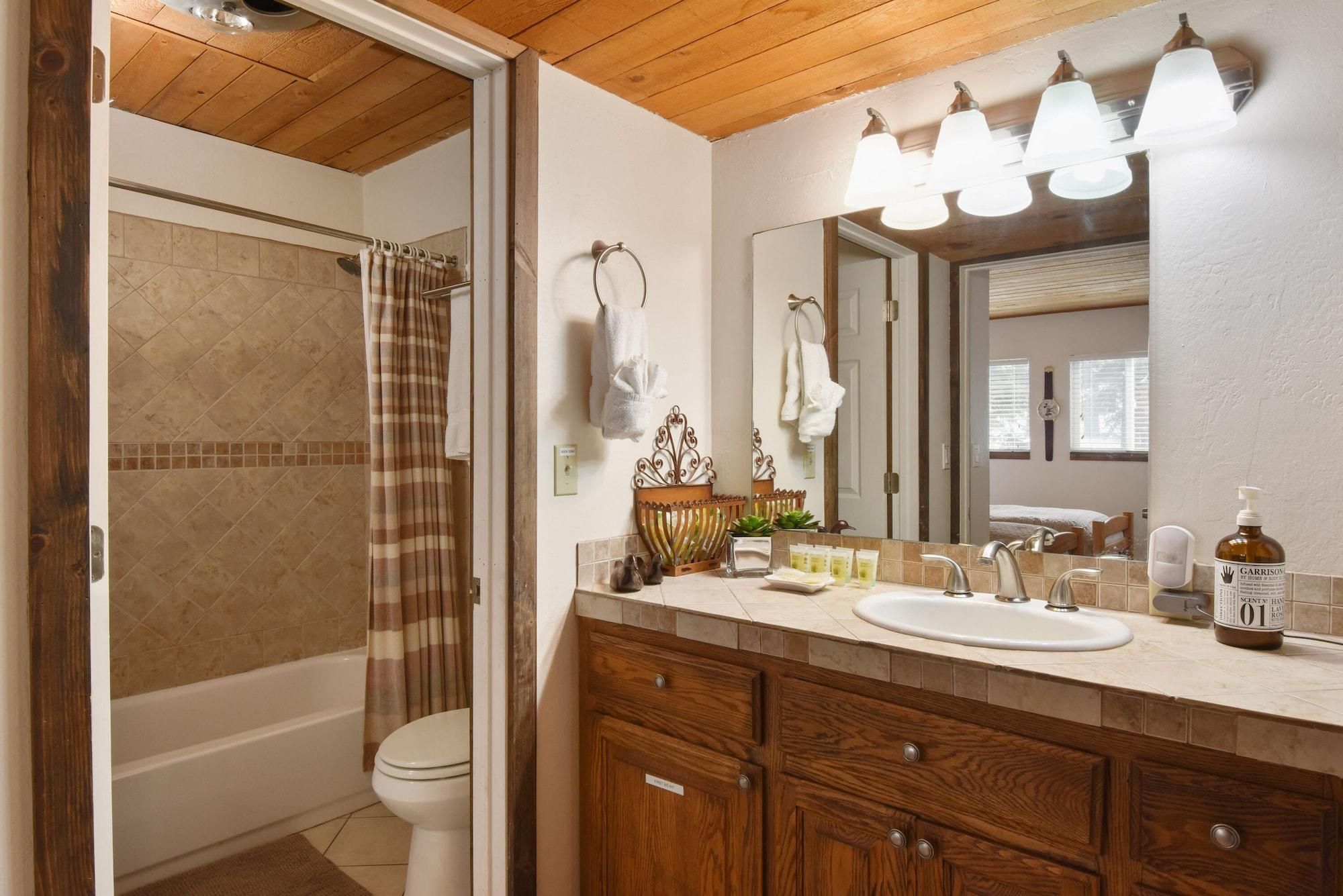 A bathroom with a shower, toilet, vanity with a sink, mirror, and towel rack.