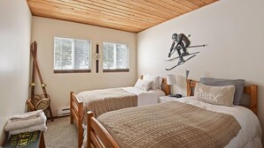 A bedroom with two beds, a wooden ceiling, and a ski-themed wall decoration. - Alpine Manor Retreat (Olympic Valley)