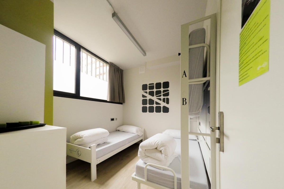 Un dormitorio con dos camas individuales, una ventana y una puerta, y una cama en el otro lado.