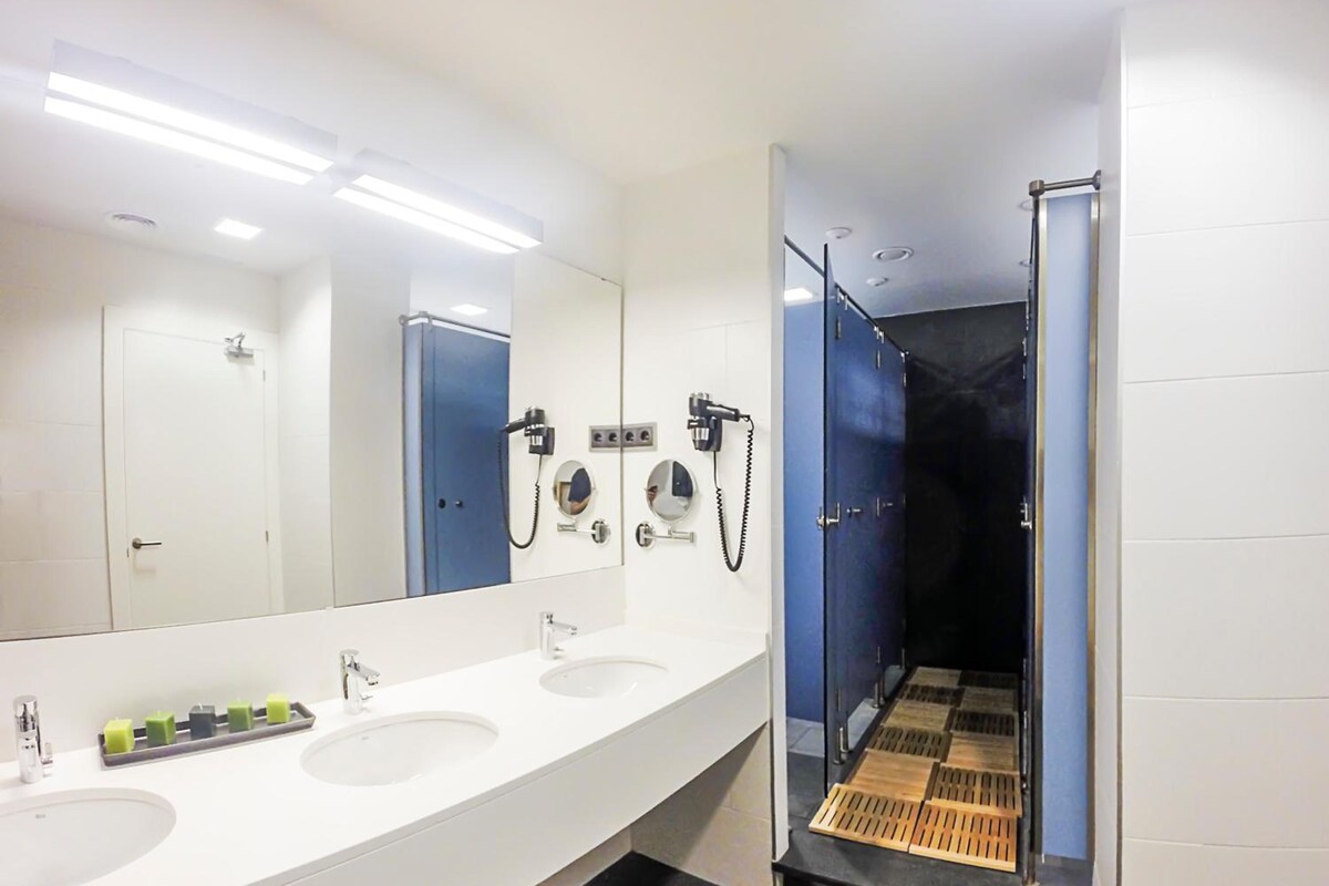 A modern bathroom with three sinks, a large mirror, and a shower area.