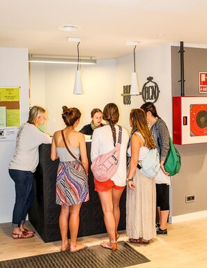 A reception area with a counter, a bulletin board, and a fire alarm. - Room018bcn (Barcelona)