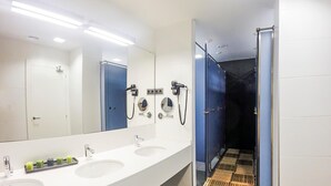Un baño moderno con tres lavamanos, un espejo grande y cabina de ducha.