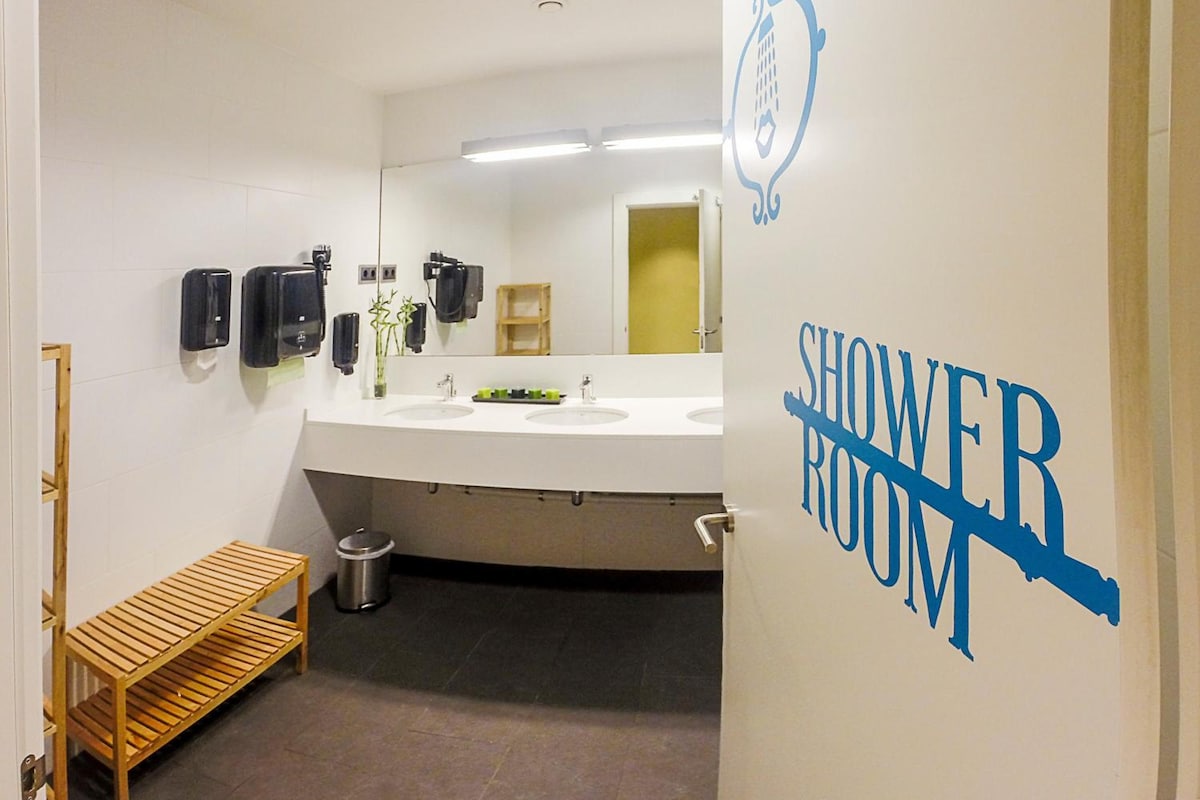 A modern shower room with two sinks, a bench, and a mirror.