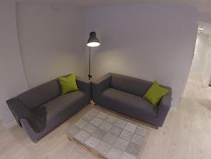 A corner room with two grey sofas, a small coffee table, and a floor lamp. - Room018bcn (Barcelona)