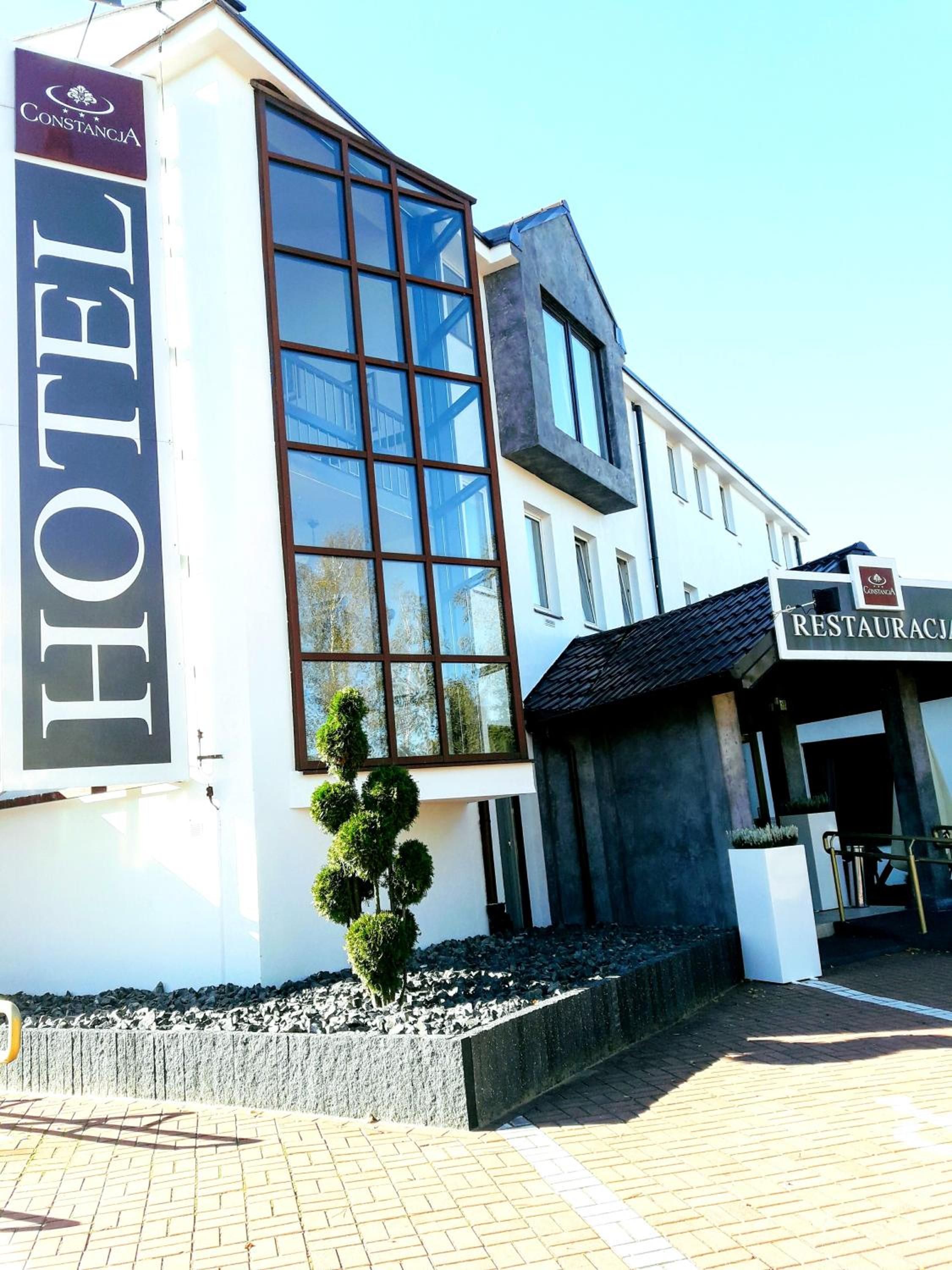 A modern hotel with a prominent 'HOTEL' sign, a restaurant, and a well-maintained outdoor area with a small tree.