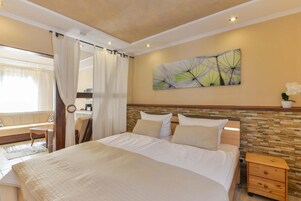 Habitación de hotel con una cama grande, un revestimiento de piedra decorativo, un cuadro y vistas al área de estar exterior.