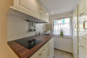 Uma cozinha com bancada de madeira, um suporte de utensílios pendurado, uma pia e uma janela com vista.