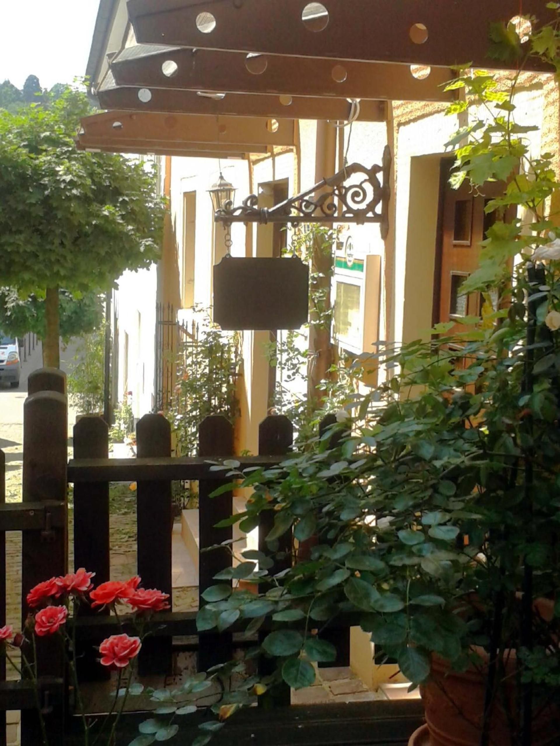 A covered outdoor area with a metal railing, a hanging sign, and potted plants.