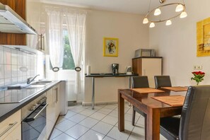 A compact kitchen with a dining area, a coffee maker, and a microwave on the counter. - Apparthaus Pfeifer (Baden-Baden)