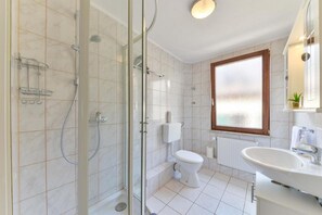 Un baño moderno con ducha de vidrio, inodoro y lavamanos.