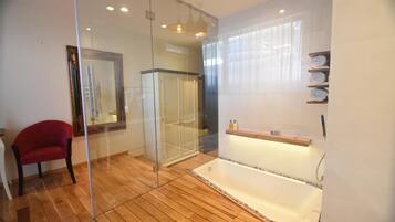 Un baño moderno con cabina de ducha de vidrio, suelo de madera, una silla roja y un estante empotrado con toallas.