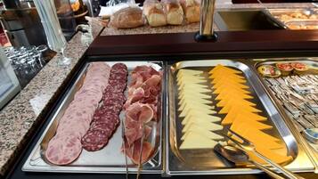 Un bufé con carnes frías, quesos y pan.