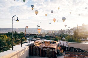 Una terraza en la azotea con vistas a un paisaje urbano y globos aerostáticos en el cielo.