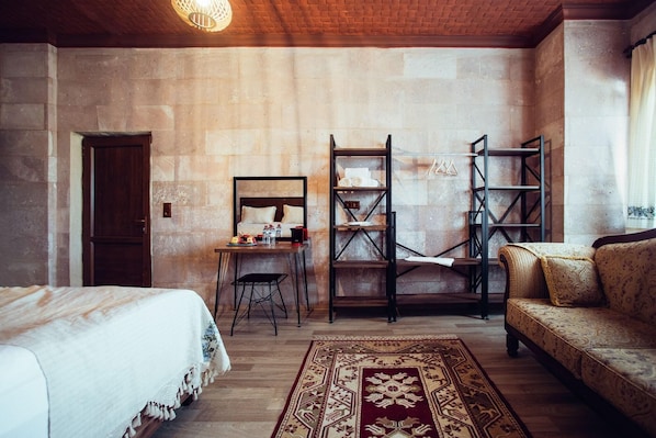 Una habitación con cama, escritorio, silla, sofá y alfombra estampada.