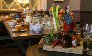 A breakfast buffet with various food items, condiments, and a selection of beverages. - Dog And Fox (London)